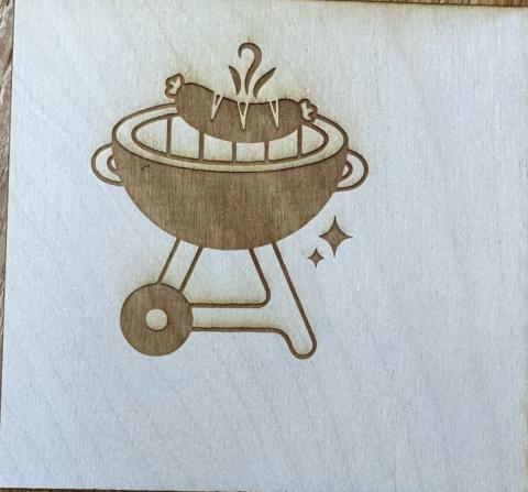 Wooden coaster with a sausage being grilled etched into the coaster