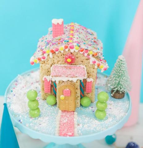 Colorful Rice Krispie Treat Cottage with candy decorations in front of blue background