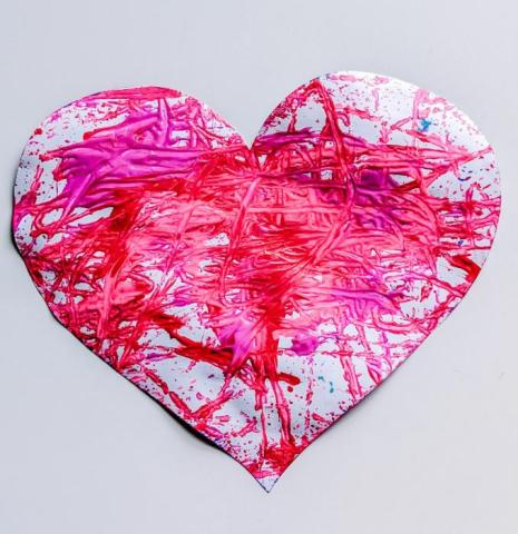 A heart shaped piece of paper with pink paint on it