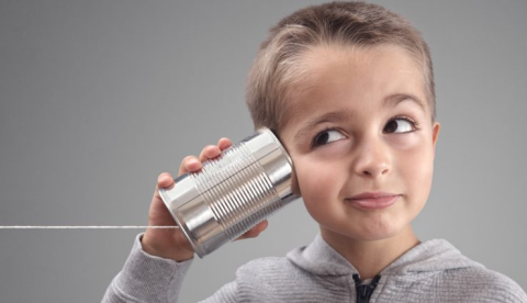 kid with ear against empty tin can with string going off to the side