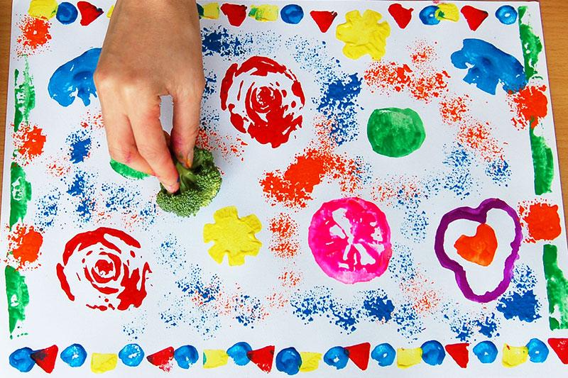 Person holding broccoli to make colorful artwork