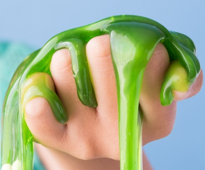 Hand holding green slime that's oozing between the fingers.