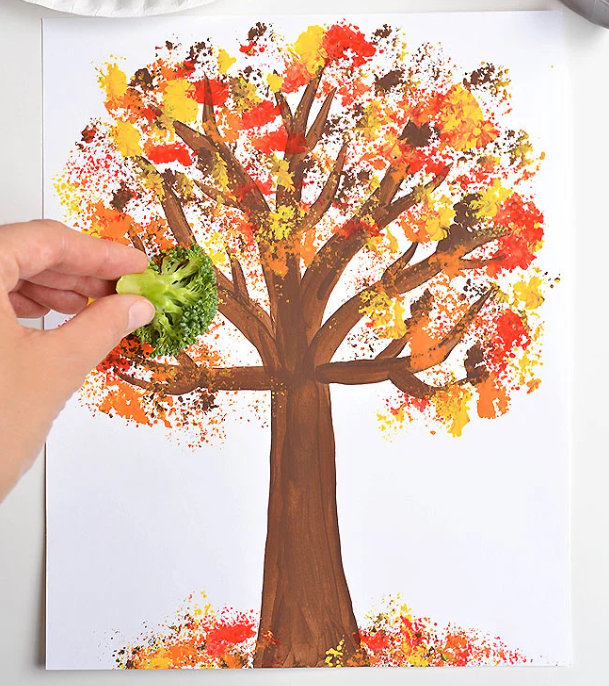 Person holding broccoli to make colorful artwork