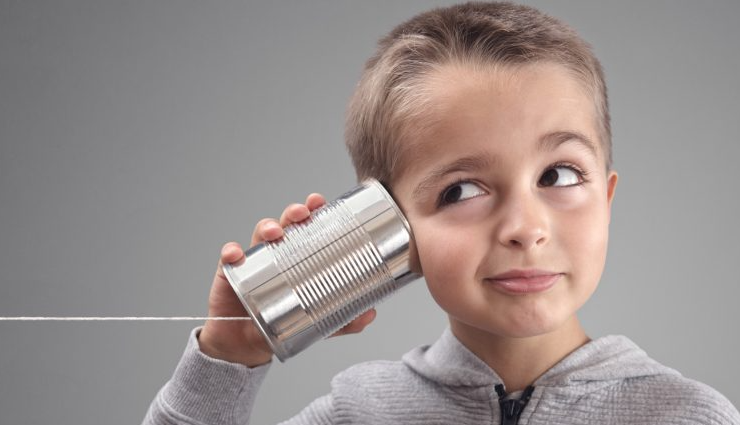 kid with ear against empty tin can with string going off to the side